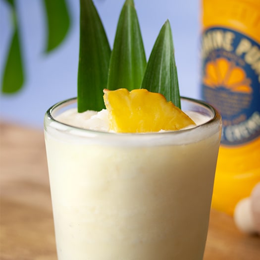 cocktail Sunshine Slushy garnished with pineapple wedge and pineapple leaves